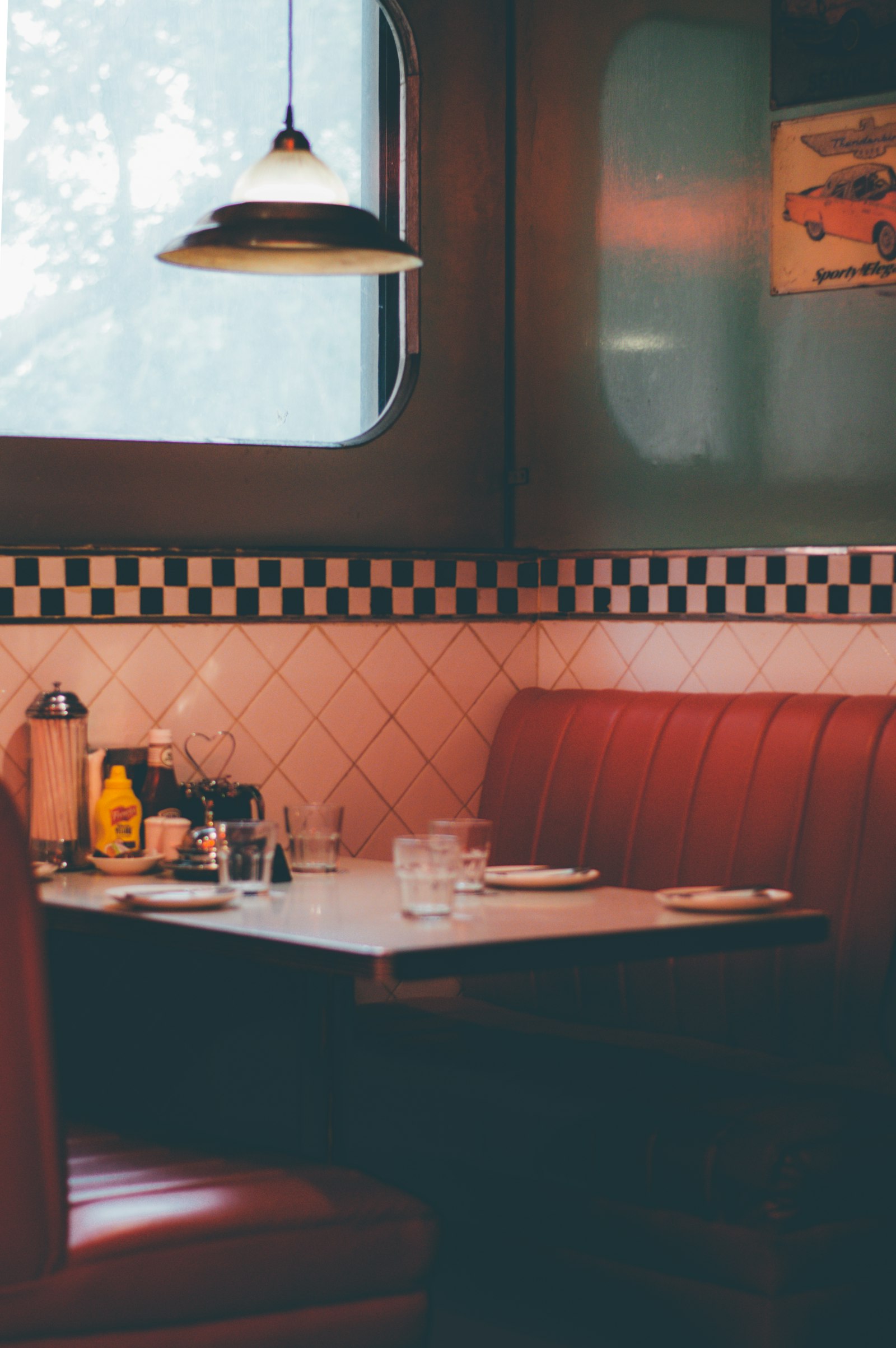 A diner booth with red seats under a hanging lamp