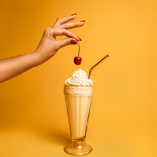 A vanilla milkshake topped with whipped cream and a cherry