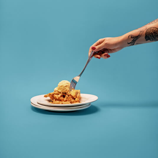 A fork lifting a bite of apple pie with ice cream